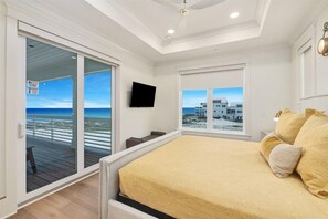 A bedroom with a bed, a television, and a view of the beach. - Amberjack (Panama City Beach)