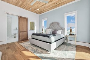 Ein Schlafzimmer mit Bett, Holzboden, Fenster und Nachttisch.