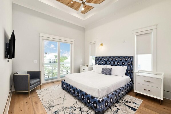 A bedroom with a large bed, a nightstand, a chair, a TV, and a window with a view. - Paradise Cove (Panama City Beach)