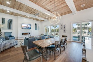 A spacious living area with a wooden ceiling, a large dining table, and a television mounted on the wall. - Blue Fin (Panama City Beach)