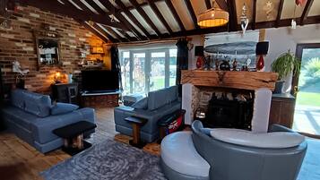 A living room with a fireplace, sofas, a television, and a brick wall.