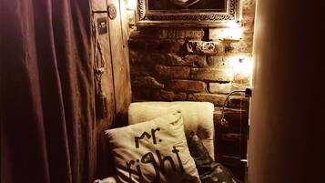 A cozy room with a brick wall, a heart-shaped mirror, and a bed with pillows.
