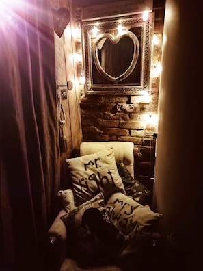 Una habitación acogedora con pared de ladrillo, un espejo con forma de corazón y una cama con almohadas.