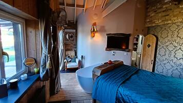 A compact bedroom with a single bed, a small bedside table, a mirror, and a window with curtains.