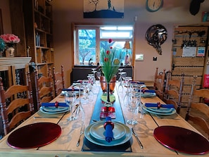 Un comedor con una mesa larga dispuesta para una comida, rodeada de sillas de madera.