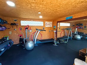 Una palestra con tapis roulant, macchinari ellittici e diversi pesi.