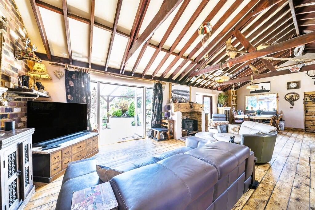 A spacious living area with a large leather sofa, a flat-screen TV, and a fireplace.