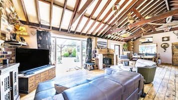 A spacious living area with a large leather sofa, a flat-screen TV, and a fireplace.