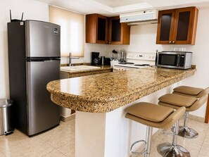 A kitchen with a granite countertop, stainless steel appliances, and wooden cabinets. - Wonderful Beachfront Condo in Cancun Hotel Zone (Cancún)