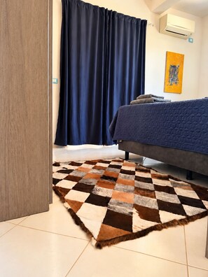 Una camera da letto con un letto, un tappeto a scacchi, tende e un condizionatore d'aria.