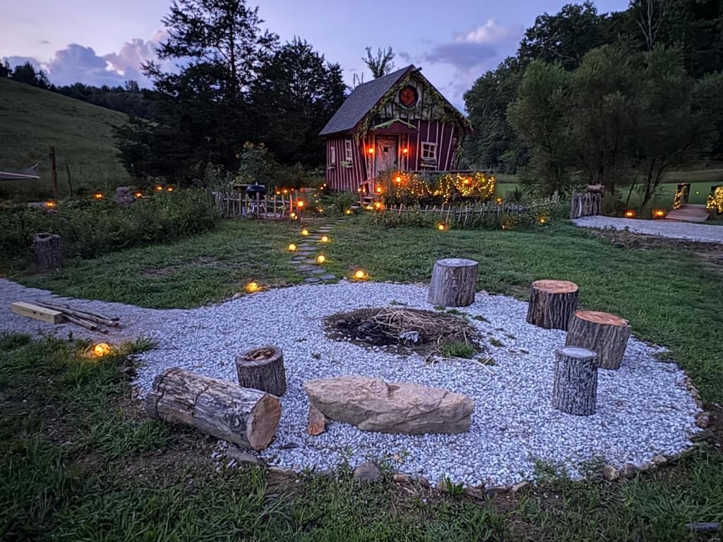 Un rustico chalet con un vialetto sterrato che vi conduce, circondato da alberi e un recinto in legno.