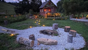Un rustico chalet con un vialetto sterrato che vi conduce, circondato da alberi e un recinto in legno.