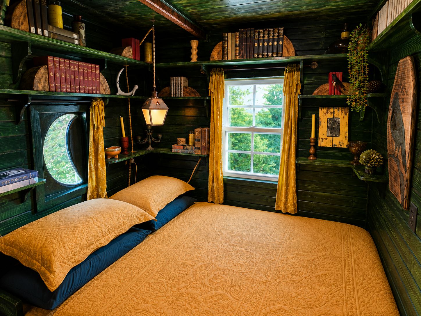 A cozy room with a bed, bookshelves, a window with curtains, and a hanging plant.