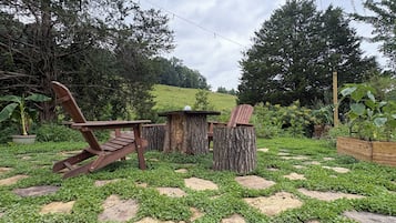 A garden area with wooden furniture, a tree stump, and a wooden structure.