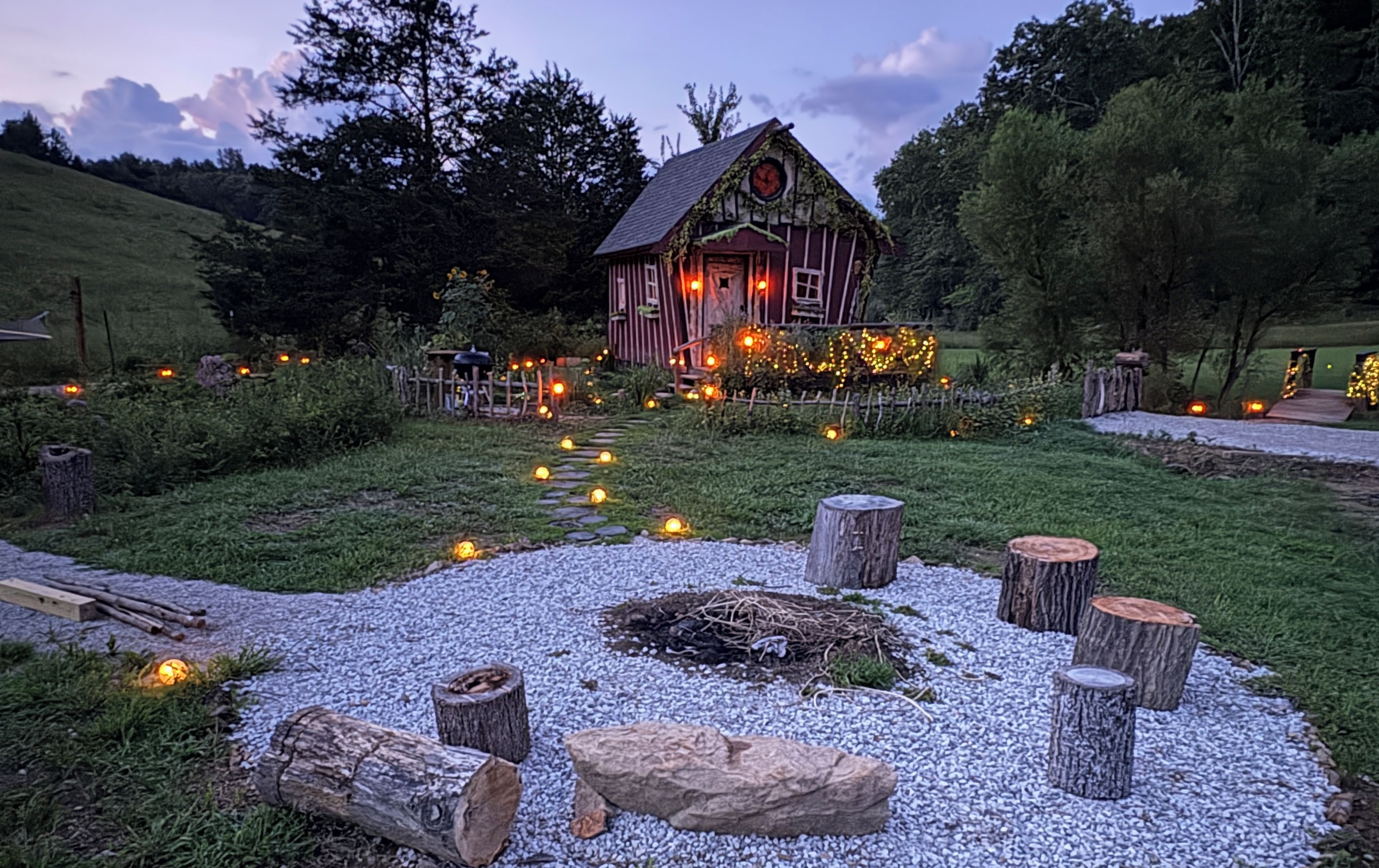 A rustic cabin with a stone pathway leading to it, surrounded by a garden with decorative lights.