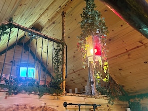 A wooden interior with a hanging light fixture, a window, and a wooden bench.