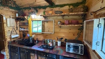 A rustic wooden cabin interior with a kitchen area featuring a sink, a toaster, and various kitchen utensils.