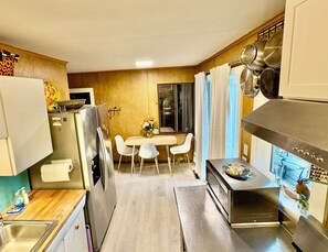 Cucina compatta con frigorifero, fornello e zona pranzo con sedie e tavolo.
