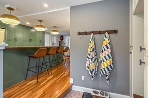 Eine moderne Küche mit Holzboden, grünen Schränken und einer Bar mit Barhocker.