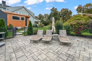 A patio with stone flooring, outdoor furniture, and a view of a house. - Peaceful Pond House | Sleeps 11, Pool, Wildlife & Room to Gather (Bethlehem)