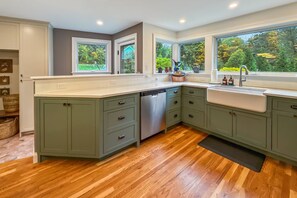 A kitchen with a dishwasher, a sink, and a window overlooking a garden. - Peaceful Pond House | Sleeps 11, Pool, Wildlife & Room to Gather (Bethlehem)
