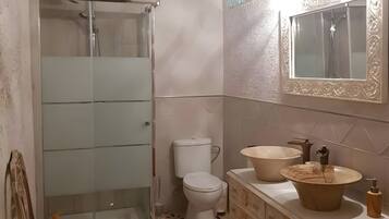 Une salle de bain avec une douche à parois de verre, des toilettes, un meuble-lavabo et un miroir.