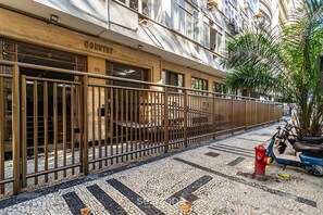 A building with a metal fence, a tiled pavement, and a red fire hydrant. - Studio in Condo. nr. Beach Pau0116 (Rio de Janeiro)