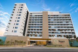 A multi-story hotel with a prominent entrance, balconies, and a clear sky. - Studio in Condo. w/ Pool & Sea View Scr0316 (Salvador)