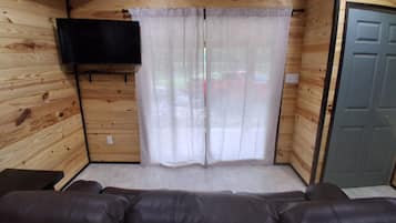 A wooden interior with a sofa, curtains, and a television mounted on the wall.