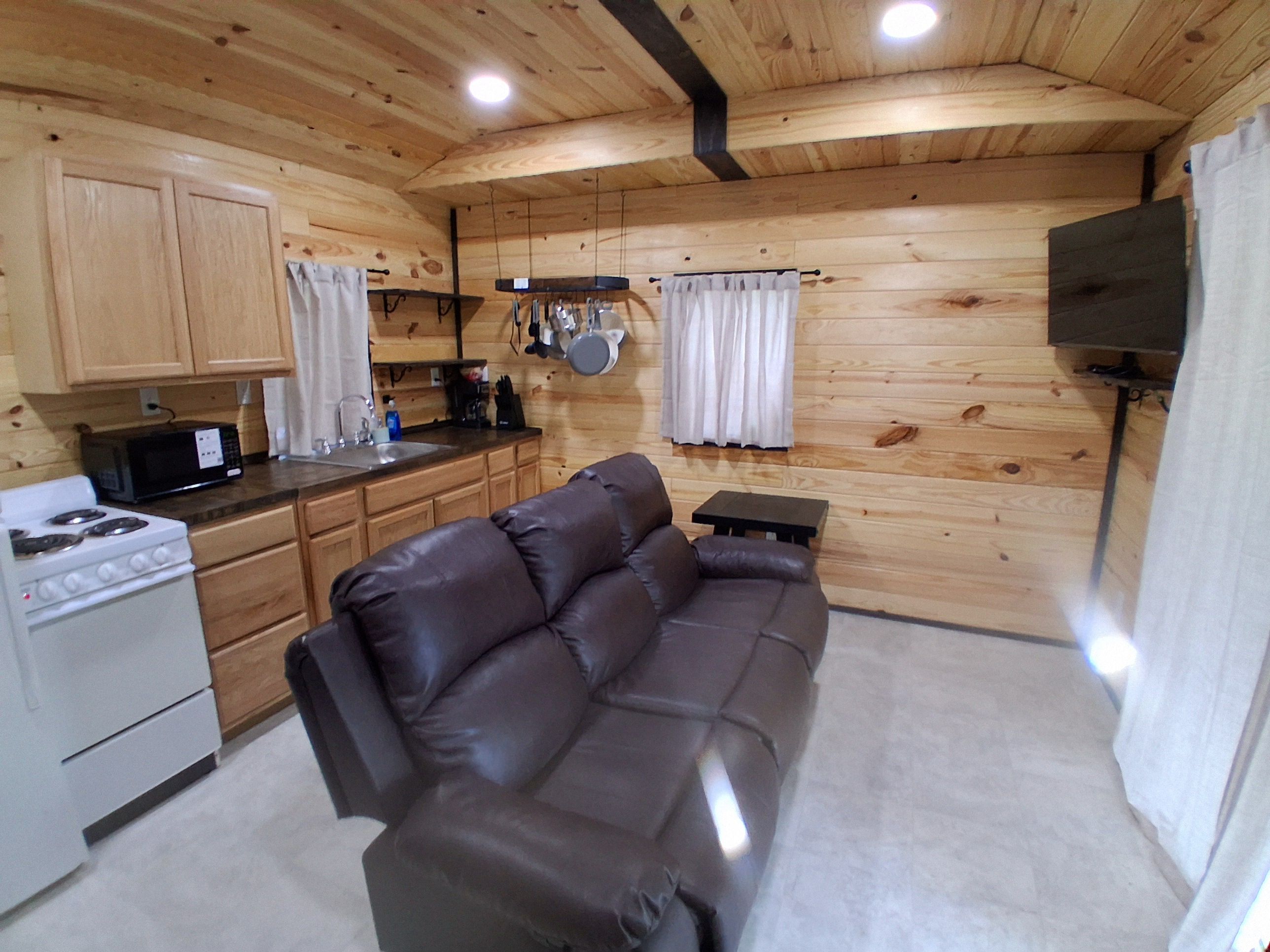 A compact kitchen with a stove, microwave, and wooden cabinets.