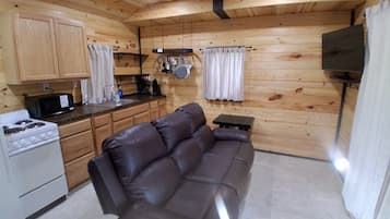 A compact kitchen with a stove, microwave, and wooden cabinets.