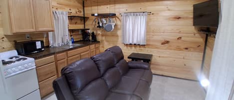 Une cuisine de taille réduite, équipée d’une cuisinière, d’un four à micro-ondes et de meubles de rangement en bois.
