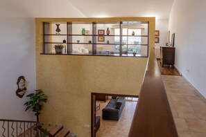 A spacious living area with a high ceiling, a wooden staircase, and a view of the outdoors through a large window. - Villa 'Verdura' with Mountain View, Wi-Fi and Air Conditioning (Inca)