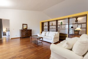 A spacious living room with a white sofa, wooden floor, and a built-in bookshelf with decorative items. - Villa 'Verdura' with Mountain View, Wi-Fi and Air Conditioning (Inca)