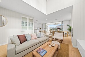 A modern living room with a sofa, coffee table, and dining area. - West End Luxe Home | Pool & BBQ | Dual living (Brisbane)