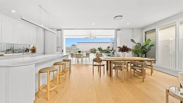 A modern kitchen with a central island, wooden chairs, and a dining area with a view.