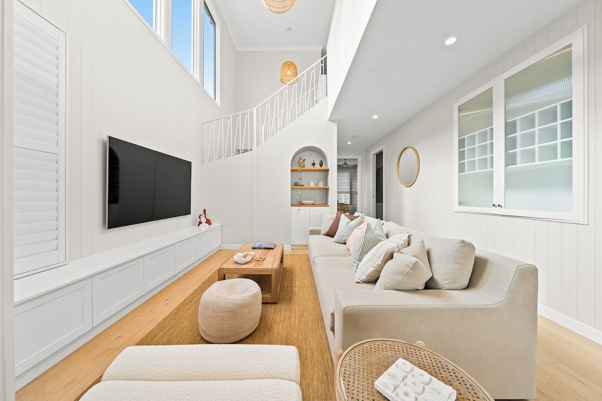 A modern living room with a flat-screen TV, a sofa, a coffee table, and a wicker basket.