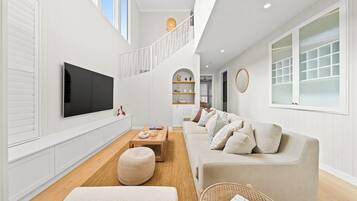 A modern living room with a flat-screen TV, a sofa, a coffee table, and a wicker basket.