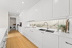 A modern kitchen with white cabinetry, a double sink, and a built-in oven. - West End Luxe Home | Pool & BBQ | Dual living (Brisbane)