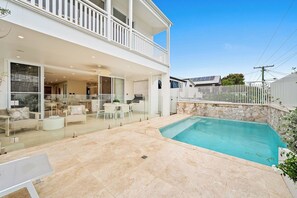 A two-story house with a swimming pool, outdoor furniture, and a stone wall. - West End Luxe Home | Pool & BBQ | Dual living (Brisbane)