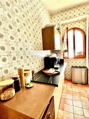 A kitchen with a tiled backsplash, a wooden countertop, a coffee maker, and a trash bin. - Villa Zattera, located on the waterfront between Porto Torres and Castelsardo. (Tonnara)