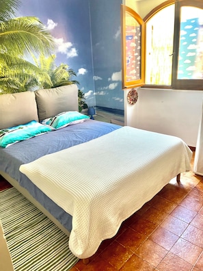 A bedroom with a bed, pillows, a window, and a wall mural. - Villa Zattera, located on the waterfront between Porto Torres and Castelsardo. (Tonnara)