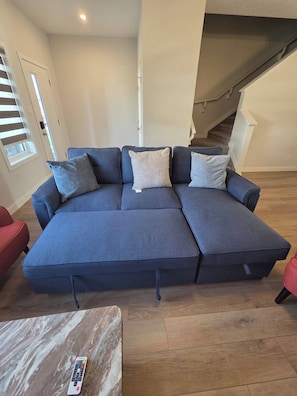 A sectional sofa with a remote control on a marble-tiled table. - Spacious Family House in Edmonton - Perfect for a Comfortable Stay (Edmonton)