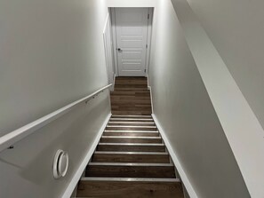 A narrow, wooden-floored stairway leading to a white door at the top. - Cozy Retreat With Private Entrance in Edmonton (Edmonton)