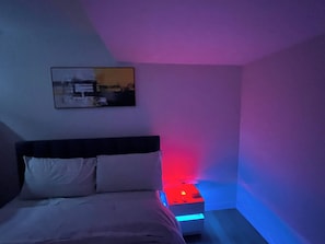 A bedroom with a bed, a bedside table with a red light, and a framed picture on the wall. - Cozy Retreat With Private Entrance in Edmonton (Edmonton)