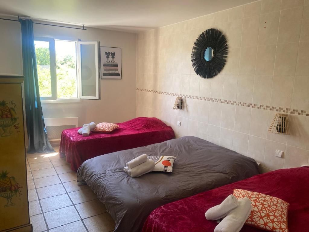 Habitación de hotel con dos camas, una ventana con cortinas, un espejo montado en la pared y un muro con azulejos.