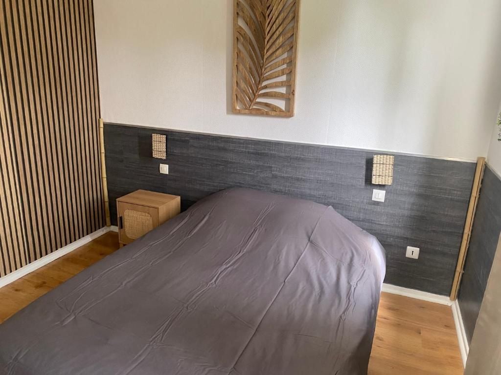 Ein Schlafzimmer mit einem Bett, einem kleinen Nachttisch, einer dekorativen Wandverkleidung und einer Wandleuchte.