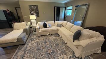 A living room with a sectional sofa, a chaise lounge, a patterned rug, and a large mirror.