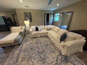A living room with a sectional sofa, a chaise lounge, a patterned rug, and a large mirror. - High Springs Hideaway / Country Charm & Wildlife (High Springs)