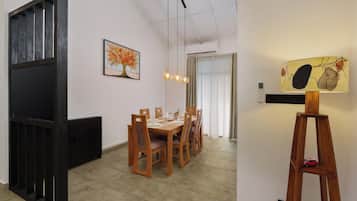 Un coin repas avec une table et des chaises en bois, un tableau accroché au mur et une lampe posée sur un pied.